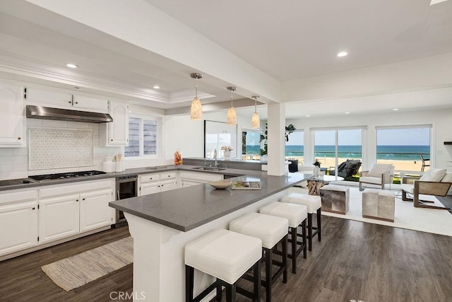 kitchen with sink, a water view, white cabinetry, a kitchen breakfast bar, and beverage cooler