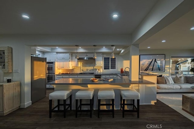 kitchen with sink, stainless steel appliances, tasteful backsplash, a kitchen bar, and kitchen peninsula