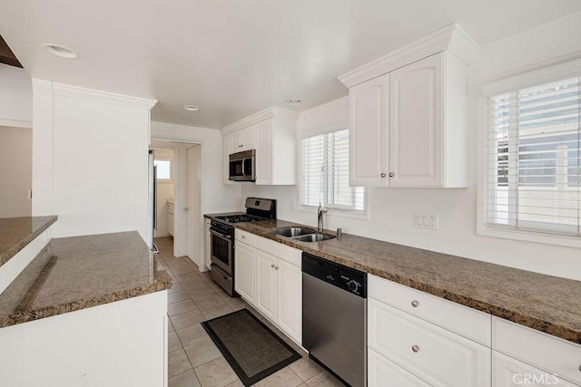 kitchen with light tile patterned flooring, appliances with stainless steel finishes, sink, white cabinets, and dark stone counters