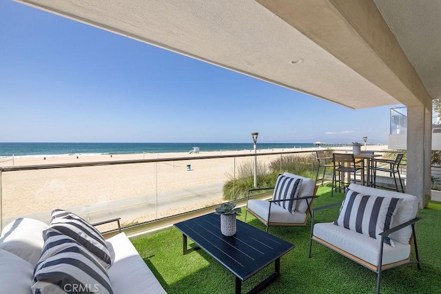 balcony with a view of the beach, an outdoor living space, and a water view