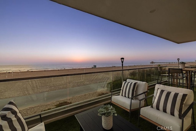 balcony at dusk featuring a water view