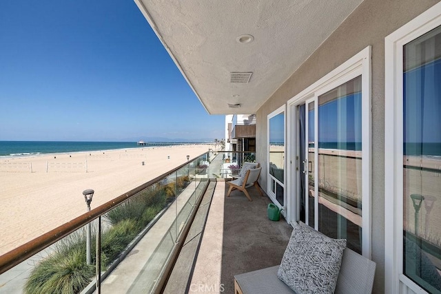 balcony featuring a beach view and a water view