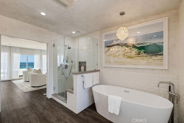 bathroom with an inviting chandelier, hardwood / wood-style floors, independent shower and bath, and a water view