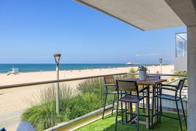 balcony featuring a view of the beach and a water view