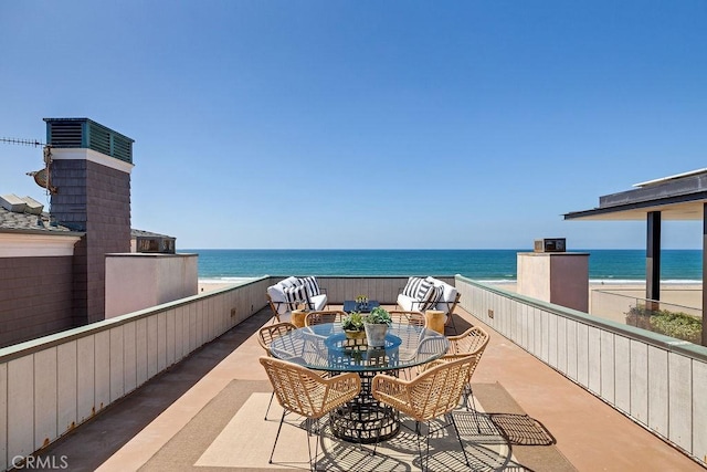 balcony featuring a patio area, a beach view, and a water view