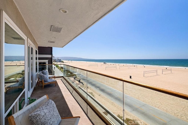 balcony featuring a water view and a beach view