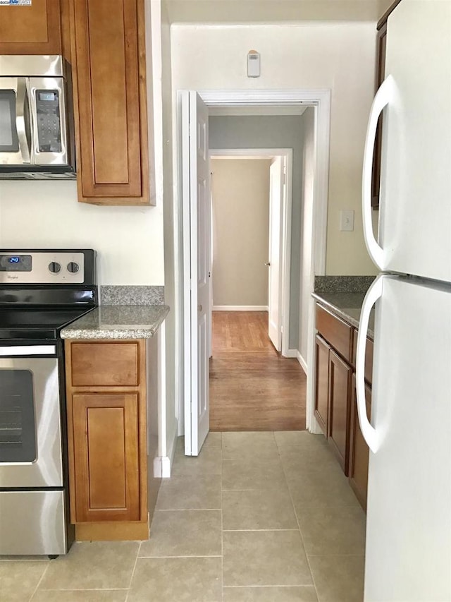 kitchen with stone countertops, light tile patterned flooring, and appliances with stainless steel finishes