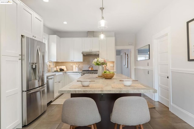 kitchen with a kitchen island, appliances with stainless steel finishes, pendant lighting, and white cabinets