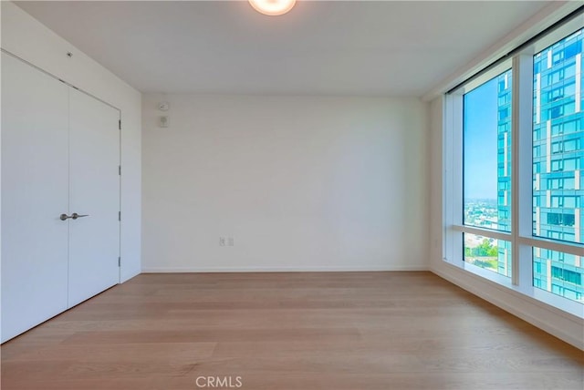 spare room featuring baseboards and light wood-type flooring