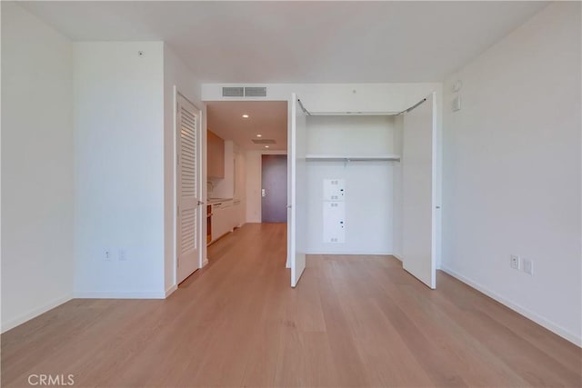 unfurnished bedroom featuring visible vents, baseboards, a closet, and light wood-style flooring