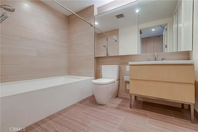 full bath with visible vents, shower / washtub combination, toilet, vanity, and tile walls