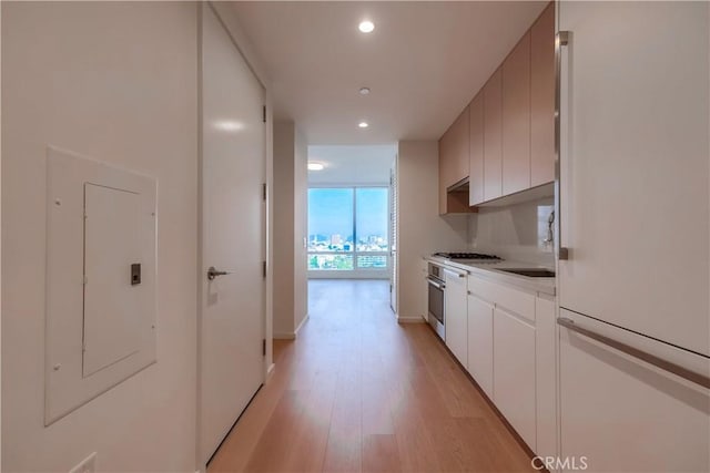 kitchen featuring light wood-style flooring, electric panel, recessed lighting, oven, and expansive windows