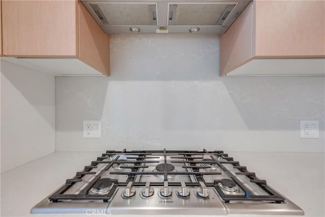 room details featuring light countertops, ventilation hood, and stainless steel gas cooktop