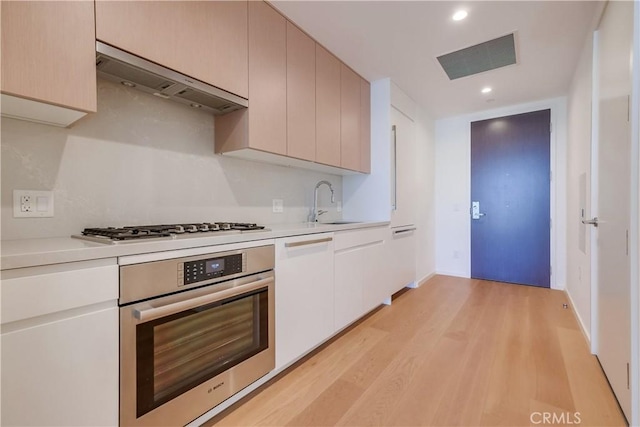 kitchen featuring visible vents, under cabinet range hood, stainless steel appliances, light wood-style floors, and light countertops