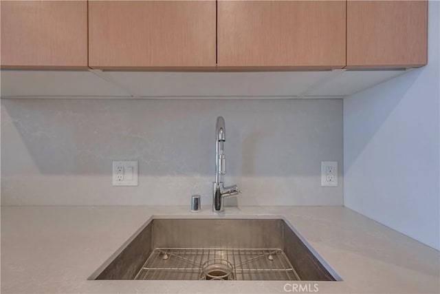 room details featuring light countertops, light brown cabinets, and a sink