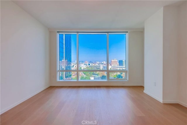 empty room with baseboards, a view of city, and wood finished floors