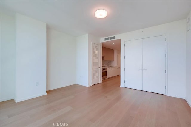 unfurnished bedroom featuring light wood-style floors, visible vents, and baseboards