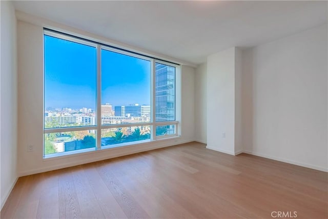 spare room with a wealth of natural light, baseboards, a view of city, and wood finished floors