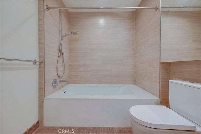 bathroom with toilet, tile walls, and washtub / shower combination