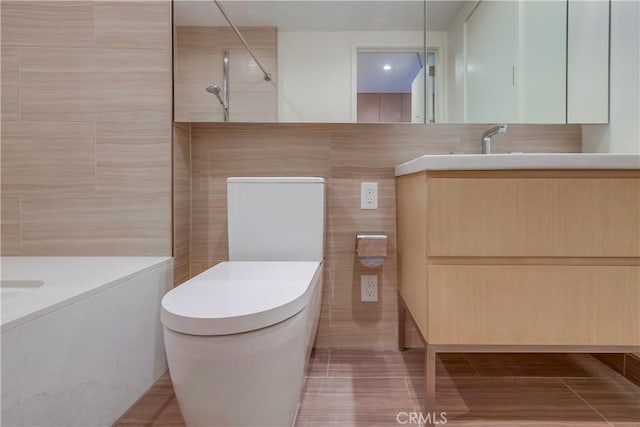 full bathroom with a tile shower, toilet, tile walls, and vanity