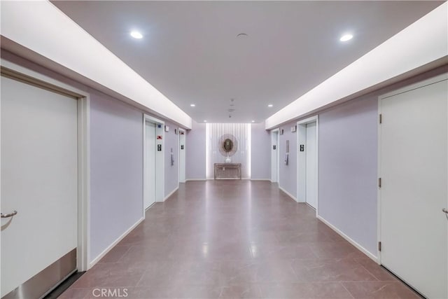 hall with elevator, recessed lighting, and baseboards