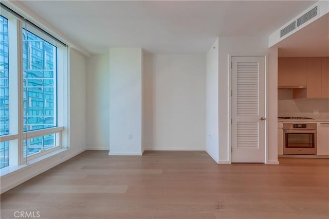 spare room featuring visible vents, baseboards, and light wood finished floors