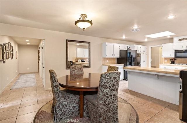 dining area with light tile patterned flooring and a skylight