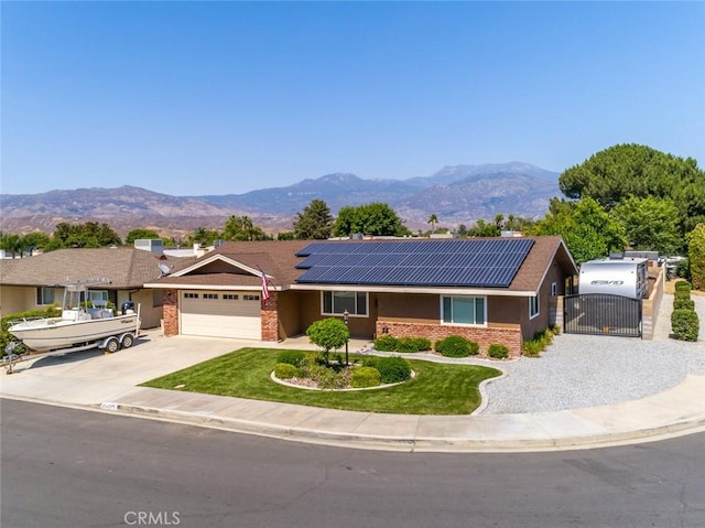 ranch-style house featuring a garage, a mountain view, and solar panels