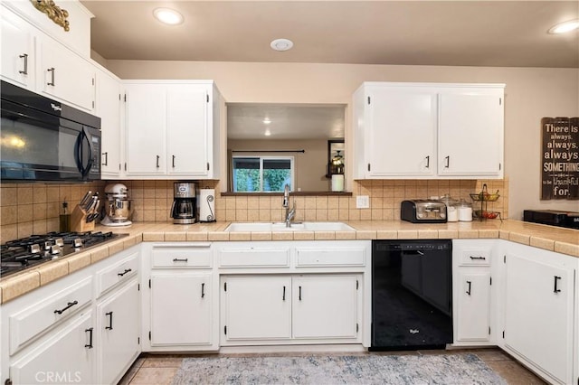 kitchen with white cabinetry, sink, backsplash, and black appliances