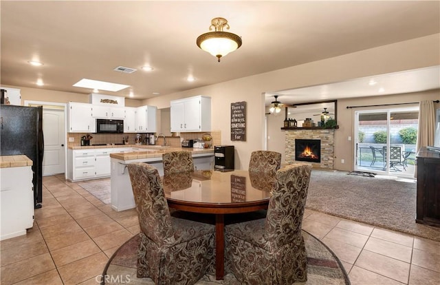 carpeted dining space featuring a fireplace and ceiling fan