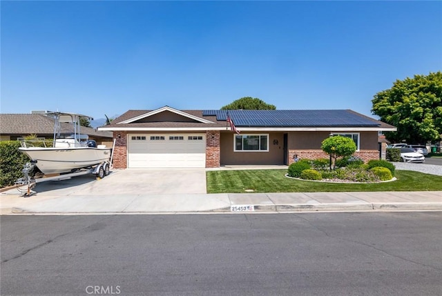 ranch-style home featuring a garage, a front lawn, and solar panels