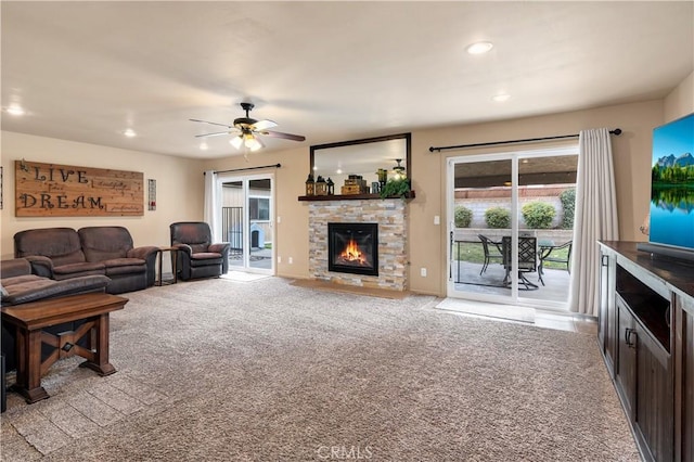 living room with ceiling fan, light carpet, and a fireplace