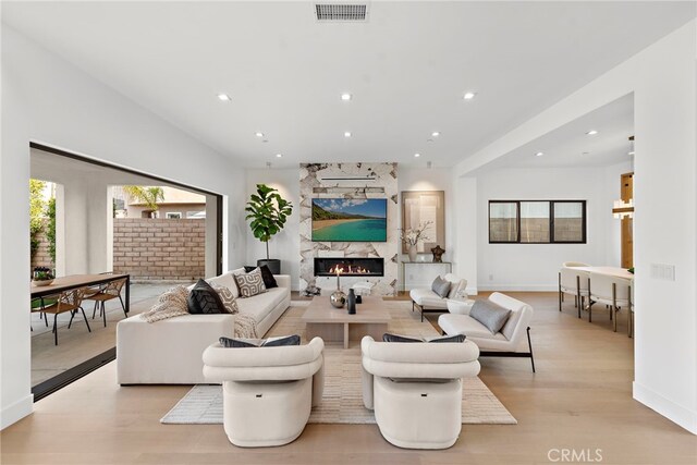 living room with a fireplace and light wood-type flooring