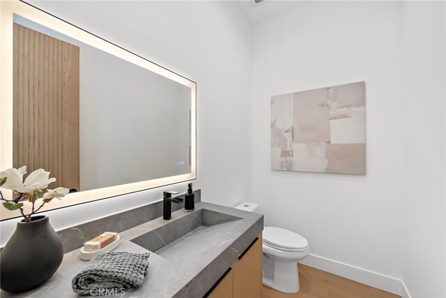 bathroom with wood-type flooring, toilet, and vanity