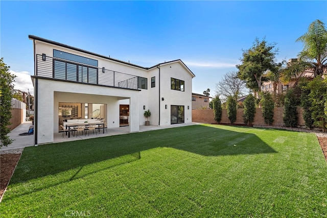 back of property featuring a balcony, a patio area, and a lawn