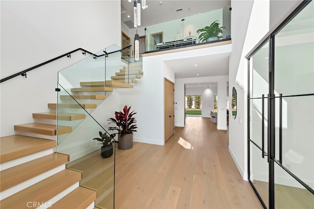 entrance foyer with a towering ceiling and wood-type flooring