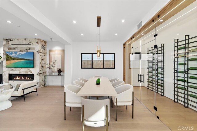 dining area with a high end fireplace and light hardwood / wood-style floors