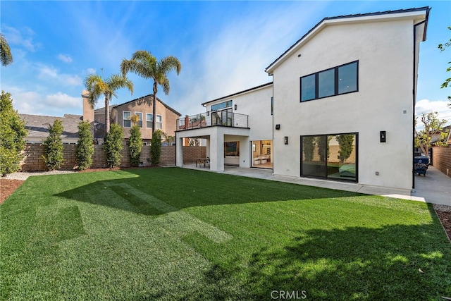 rear view of property with a yard, a patio area, and a balcony