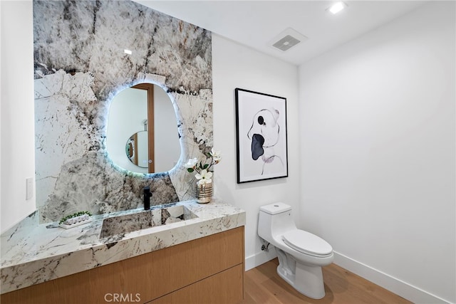 bathroom with hardwood / wood-style flooring, vanity, and toilet