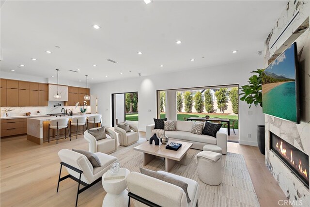 living room featuring a high end fireplace, sink, and light hardwood / wood-style floors