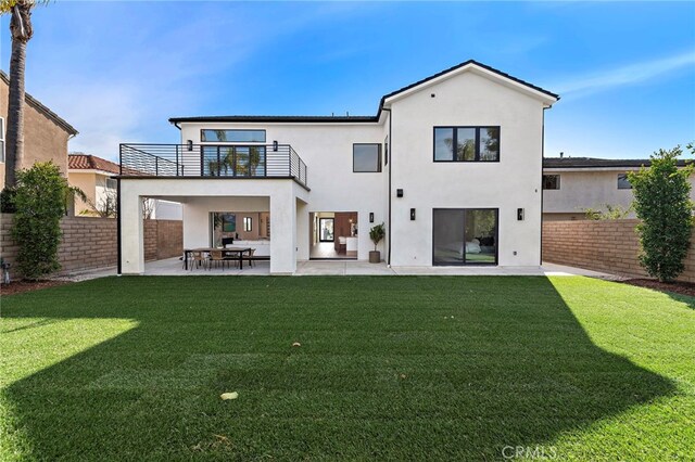 rear view of house with a patio, a balcony, and a lawn