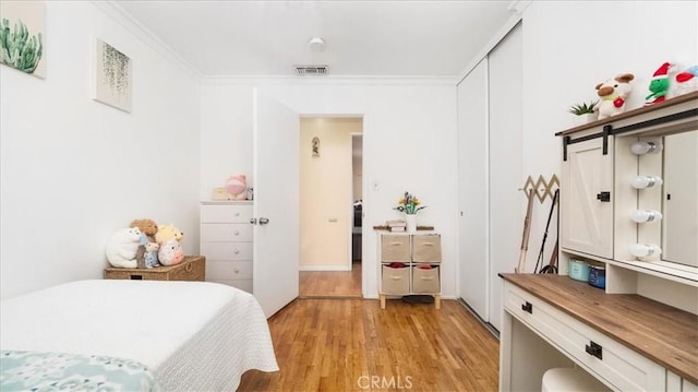 bedroom featuring visible vents, ornamental molding, and light wood-style flooring