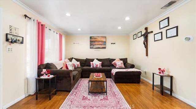 living room with visible vents, crown molding, and wood finished floors