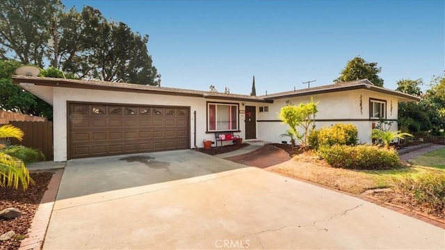 ranch-style house with a garage, driveway, fence, and stucco siding