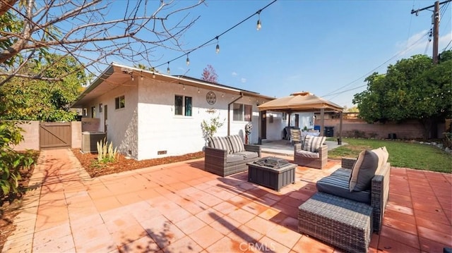 rear view of house with an outdoor living space with a fire pit, a gazebo, crawl space, a patio area, and a gate