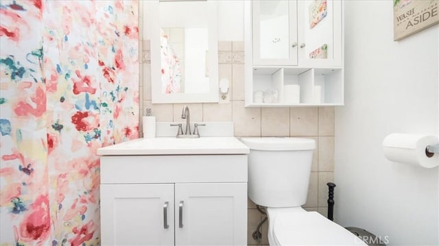 bathroom with toilet, tile walls, vanity, and decorative backsplash