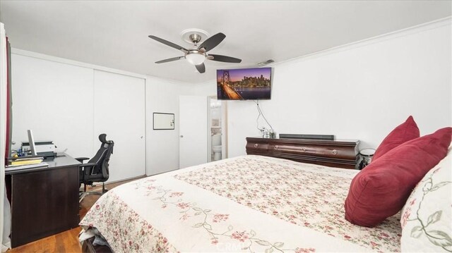 bedroom with ceiling fan, ornamental molding, a closet, and wood-type flooring