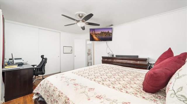 bedroom with crown molding, a closet, visible vents, a ceiling fan, and wood finished floors