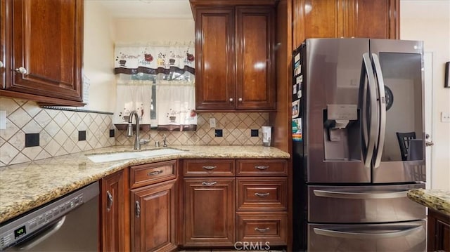 kitchen with stainless steel appliances, a sink, light stone counters, and decorative backsplash