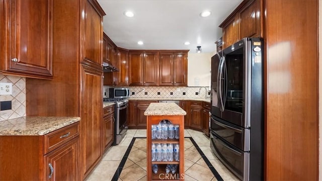 kitchen featuring light stone counters, under cabinet range hood, recessed lighting, appliances with stainless steel finishes, and tasteful backsplash